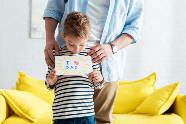 częściowy widok człowieka w pobliżu uśmiechniętego syna trzymając ręcznie robionych ojców dzień kartki z życzeniami z literami i symbolem serca - Zdjęcie, obraz