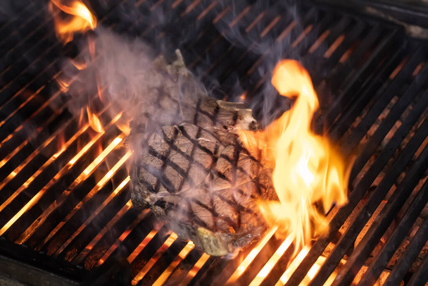 Carne de res en la parrilla con llamas. Carne de vacuno T-bone steaks (dallas steaks) en la parrilla con llamas
. - Foto, imagen