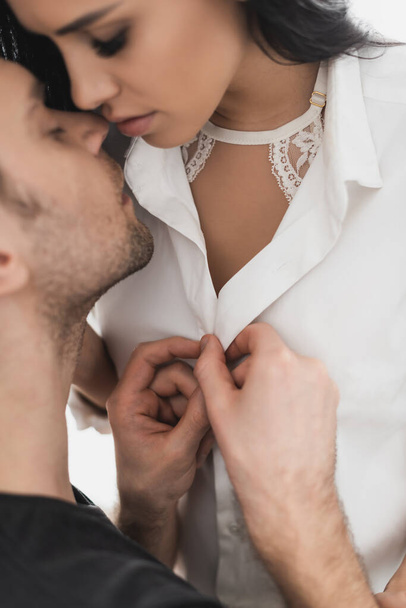 Selective focus of man unbuttoning shirt and kissing beautiful girlfriend  - Фото, зображення
