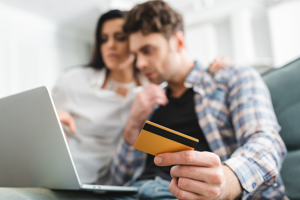 Вибіркове фокусування людини, яка тримає кредитну картку, використовуючи ноутбук біля подруги вдома.  - Фото, зображення