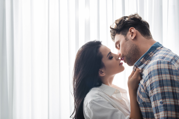 Mulher bonita beijando namorado perto da janela em casa
 - Foto, Imagem