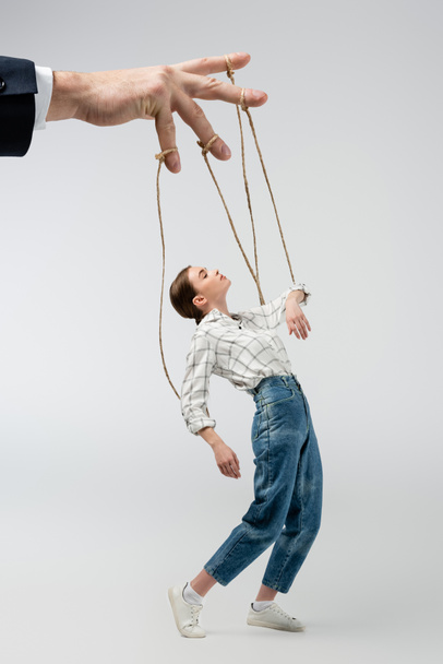 cropped view of puppeteer holding marionette on strings isolated on grey - Fotografie, Obrázek