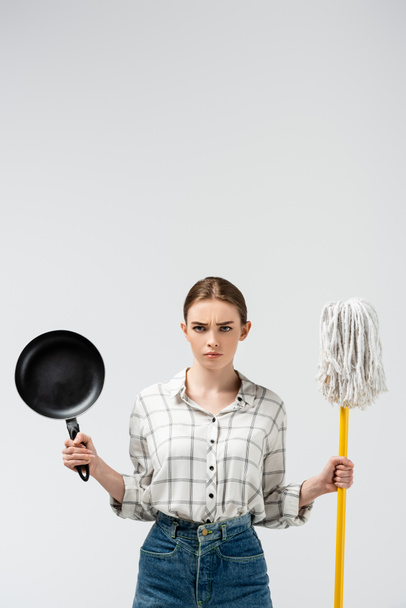 attractive girl posing like puppet with mop and frying pan isolated on grey - Photo, Image