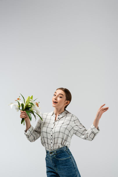 happy attractive girl posing like puppet with flowers isolated on grey - Φωτογραφία, εικόνα