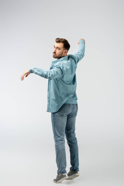 young man posing like puppet isolated on grey - Foto, afbeelding