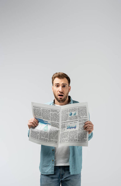 shocked young man with newspaper isolated on grey - Fotoğraf, Görsel