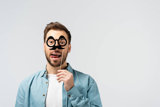 funny young man with fake mustache and glasses on stick isolated on grey - Photo, Image