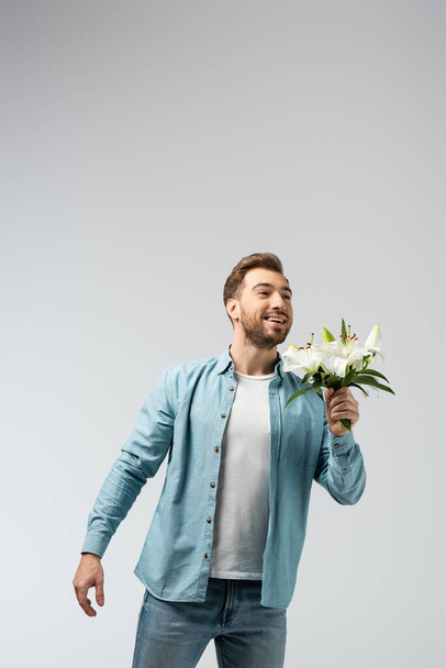 felice giovane uomo con bouquet floreale isolato su grigio - Foto, immagini