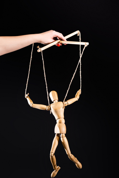 cropped view of puppeteer holding wooden marionette isolated on black - Photo, Image