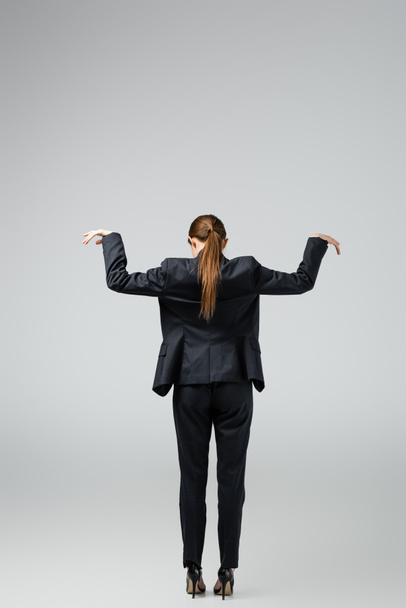 back view of businesswoman marionette in suit posing isolated on grey - Foto, Imagem