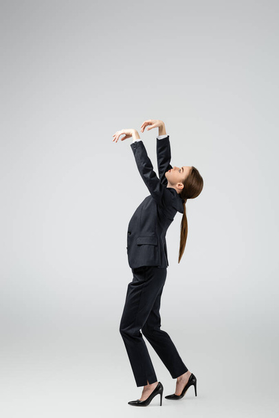 side view of businesswoman marionette in suit posing isolated on grey - Фото, зображення
