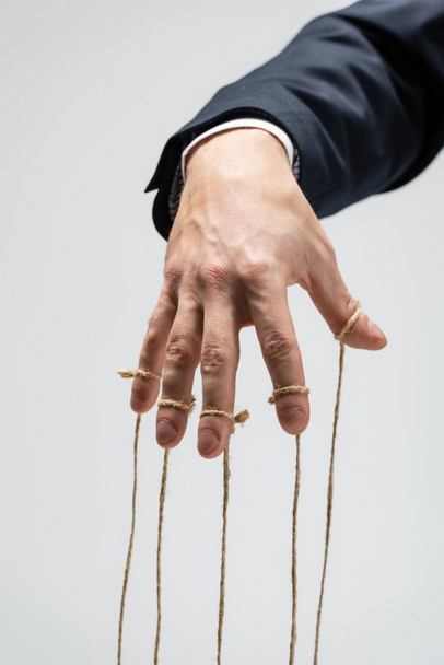 partial view of puppeteer with strings on fingers isolated on grey - Fotografie, Obrázek