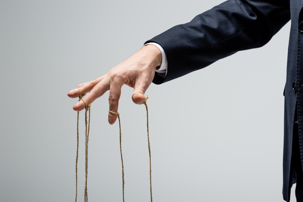 cropped view of puppeteer with strings on fingers isolated on grey - Foto, afbeelding