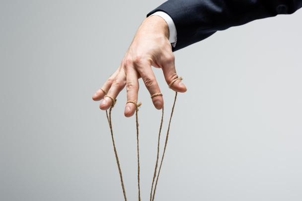 cropped view of puppeteer with strings on fingers isolated on grey - 写真・画像