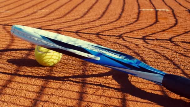 Tennis racket and tennis ball lying on a red tennis court, dolly - Footage, Video
