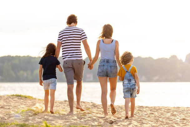 Foto de una familia de cuatro personas pasando el día en la playa
 - Foto, Imagen