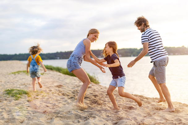 Zdjęcie czteroosobowej rodziny spędzającej dzień na plaży. - Zdjęcie, obraz