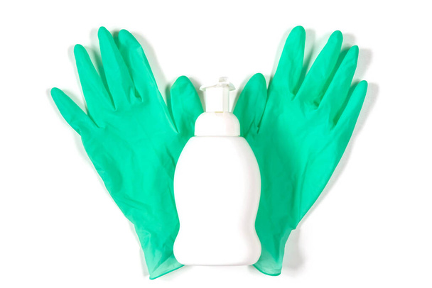 背景に隔離された緑のゴム手袋上の白いプラスチックスプレーボトル。白い背景にアルコール液体ボトルとラテックス手袋のトップビュー。ウイルスや細菌の予防ツールのフラットレイアウト - 写真・画像
