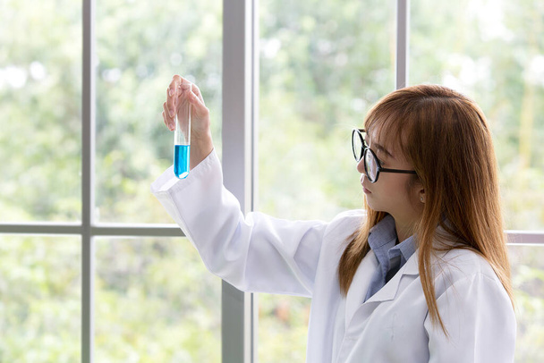 Sciene whit blue spirit mind. Wissenschaftliche Substanz blau in ihrer Hand im Labor einen Hintergrund. Schöne lächelnde Ärztin oder Wissenschaftlerin mit wissenschaftlicher Substanz organisch. - Foto, Bild