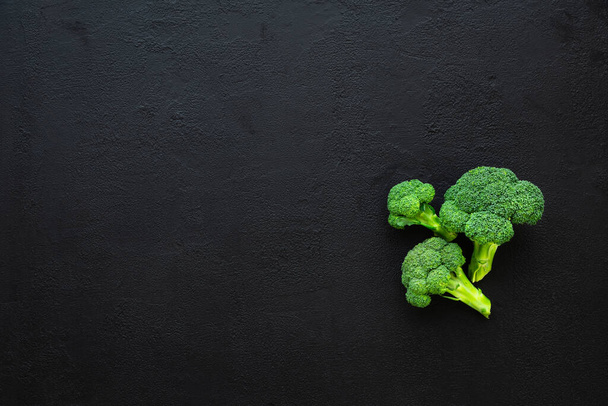 Healthy green organic raw broccoli florets on black background - Foto, imagen