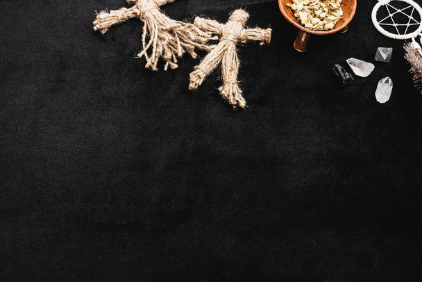 top view of voodoo dolls near sagebrush in bowl, pentagram and crystals on black - 写真・画像
