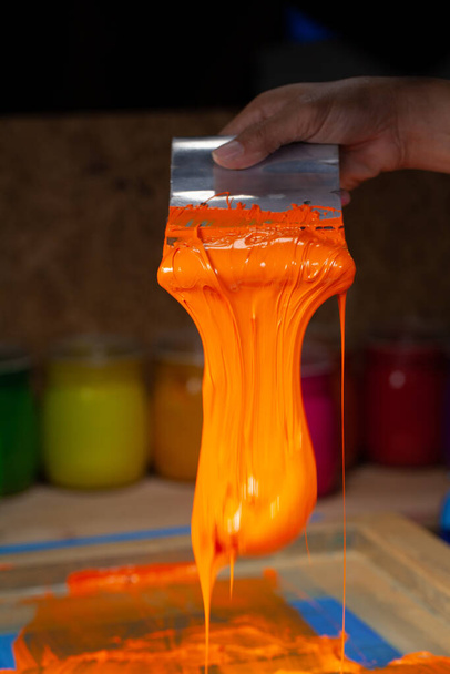 narancs színű csöpög a kézi képernyős nyomtatás során póló nyomtatása póló póló gyári. - Fotó, kép