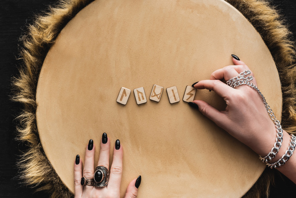 vista superior de la mujer tocando runas antiguas en la superficie de madera
  - Foto, imagen