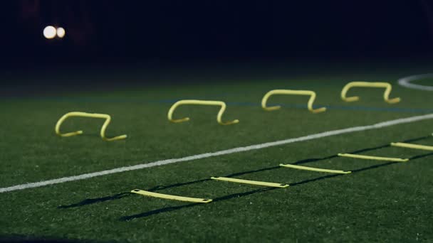 Trainingstoestellen voor behendigheid van voetbal. Professionele voetballer met behendigheidsladder en horden 's nachts, 4k - Video