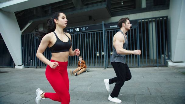 Pareja de fitness corriendo juntos en la calle urbana. Hombre entrenamiento obstáculos correr
. - Foto, Imagen