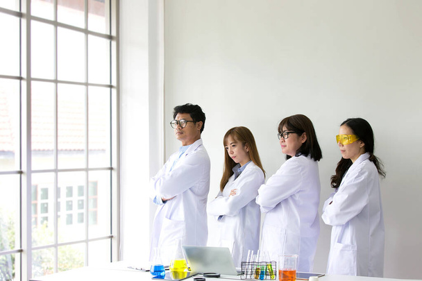 Test naukowy. Chemik bada osobliwość. Naukowiec pracujący w laboratorium. Jeden mężczyzna i trzy kobiety w laboratorium chemicznym. Azjaci. - Zdjęcie, obraz