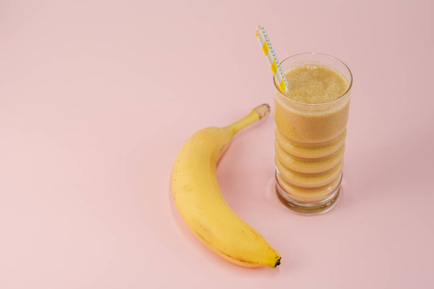One Yellow Smoothie Cocktail with Banana Standing on the Table - 写真・画像