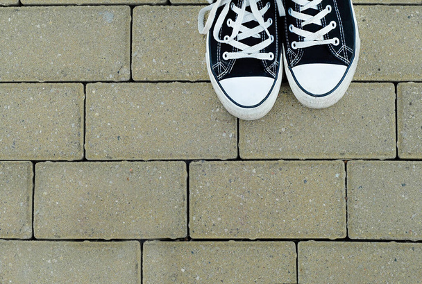 Teenager with black sneakers on the paving background, top view - Φωτογραφία, εικόνα