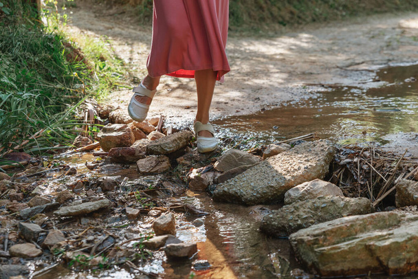 Girl on stones crosses a brook - Zdjęcie, obraz