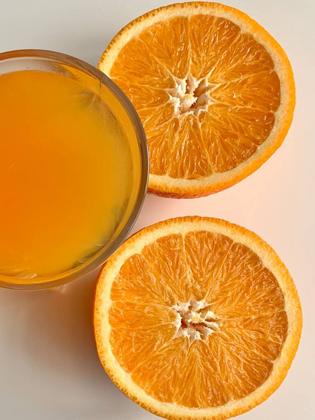 Оранжевый сок и две половинки оранга на белом фоне
 - Фото, изображение