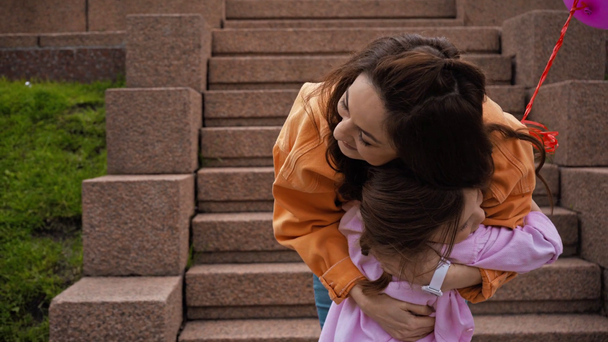 χαριτωμένο παιδί με μπαλόνια τρέχει στη μητέρα και αγκαλιάζει στο πάρκο - Πλάνα, βίντεο