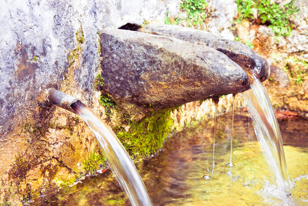 Каменный источник питьевой воды идет из горы - изображение с копировальным пространством
 - Фото, изображение