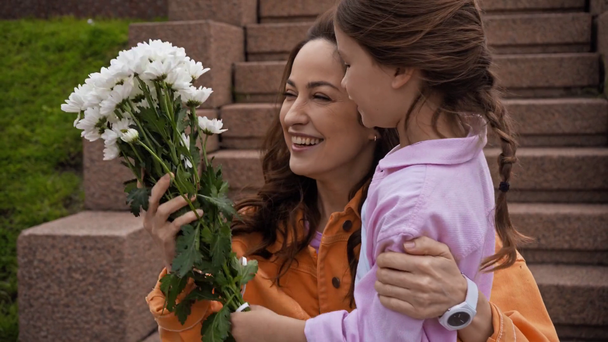 Kind schenkt glücklicher Mutter draußen Blumen  - Filmmaterial, Video