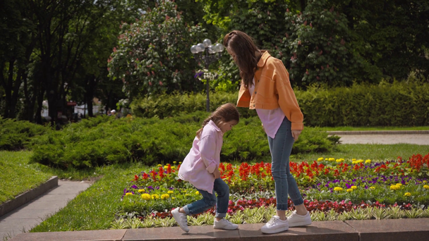 emotionele moeder en dochter stampen in de buurt van bloembed buiten  - Video