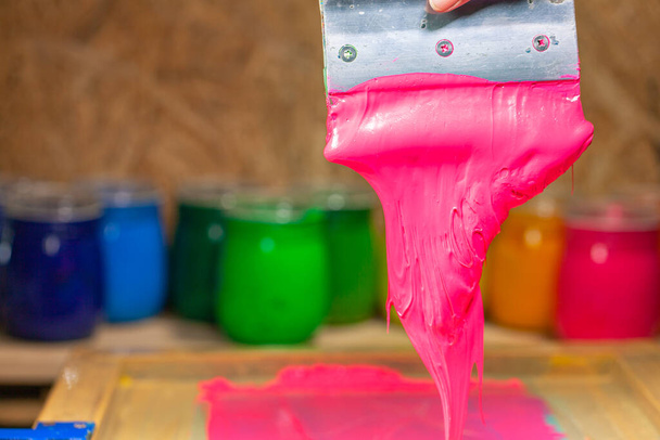 ροζ χρώμα στάζει από το χέρι οθόνη εκτύπωσης κατά την εκτύπωση μπλουζάκι - Φωτογραφία, εικόνα