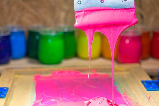pink color dripping from hand screen printing during printing tee shirt - 写真・画像