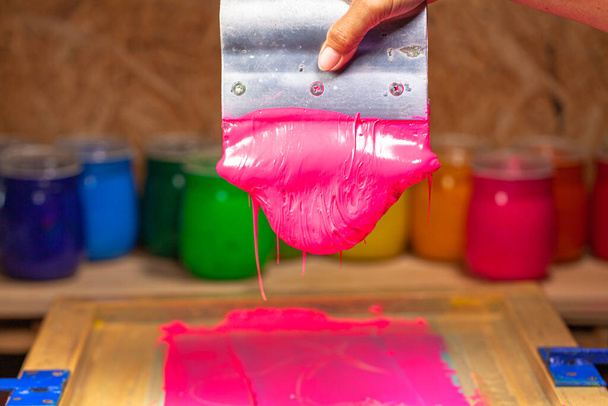 rózsaszín színű csöpög a kézi képernyős nyomtatás során póló nyomtatása - Fotó, kép