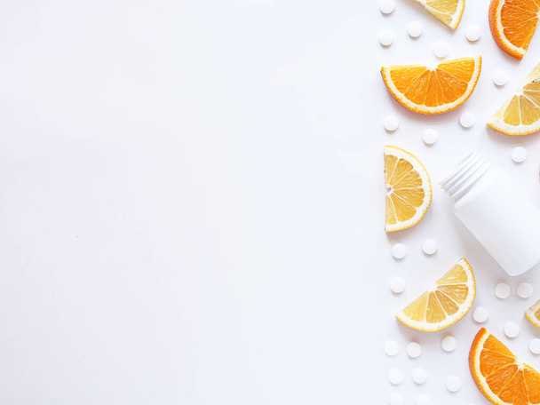 scattered vitamin pills and bottle with lemon orange on white background. Copyspace, flat lay. Concept boost immune system, medicine and tablets - Valokuva, kuva
