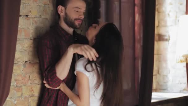 Just married couple embraces kissing and hugging standing in living room. Woman in white t shirt crazy in love with her husband. Man caresses woman back gently. Rear view. Family concept. Prores 422 - Metraje, vídeo