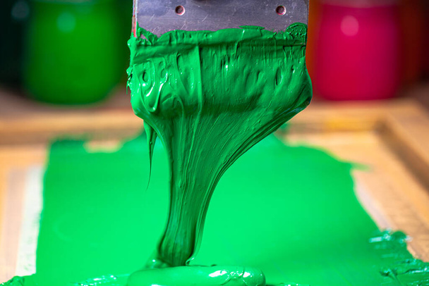 zielony kolor kapanie z sitodruku podczas drukowania koszulki tee w tee shirt fabryki. - Zdjęcie, obraz