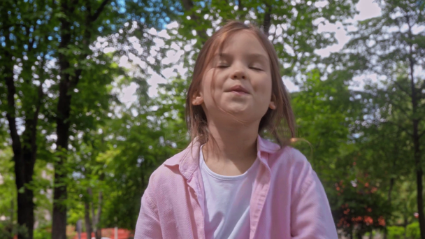 boldog gyerek leveszi orvosi maszk és nyújtózkodik a parkban  - Felvétel, videó