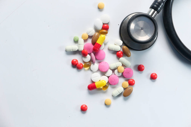 kleurrijke pillen morsen en stethoscoop op witte achtergrond  - Foto, afbeelding
