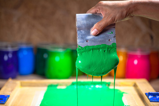groene kleur druipend van handzeefdruk tijdens het bedrukken T-shirt in T-shirt fabriek. - Foto, afbeelding