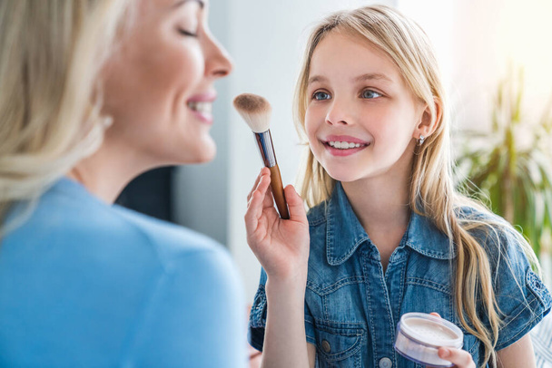 Happy loving family concept. Close up of little girl making make up her mother at home - Foto, immagini