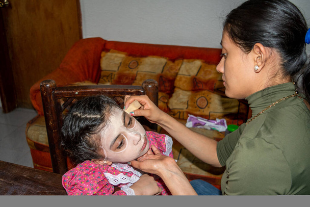 母は娘の顔にカトリーナの化粧をして祭りを祝う - 写真・画像