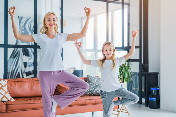 Mom and daughter practicing yoga at home, healthy family lifestyle - Fotoğraf, Görsel